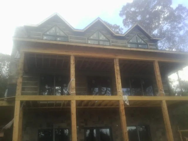 Dormers and porch framing on a large log home under construction — Roof Coating work by our crew in Lodi