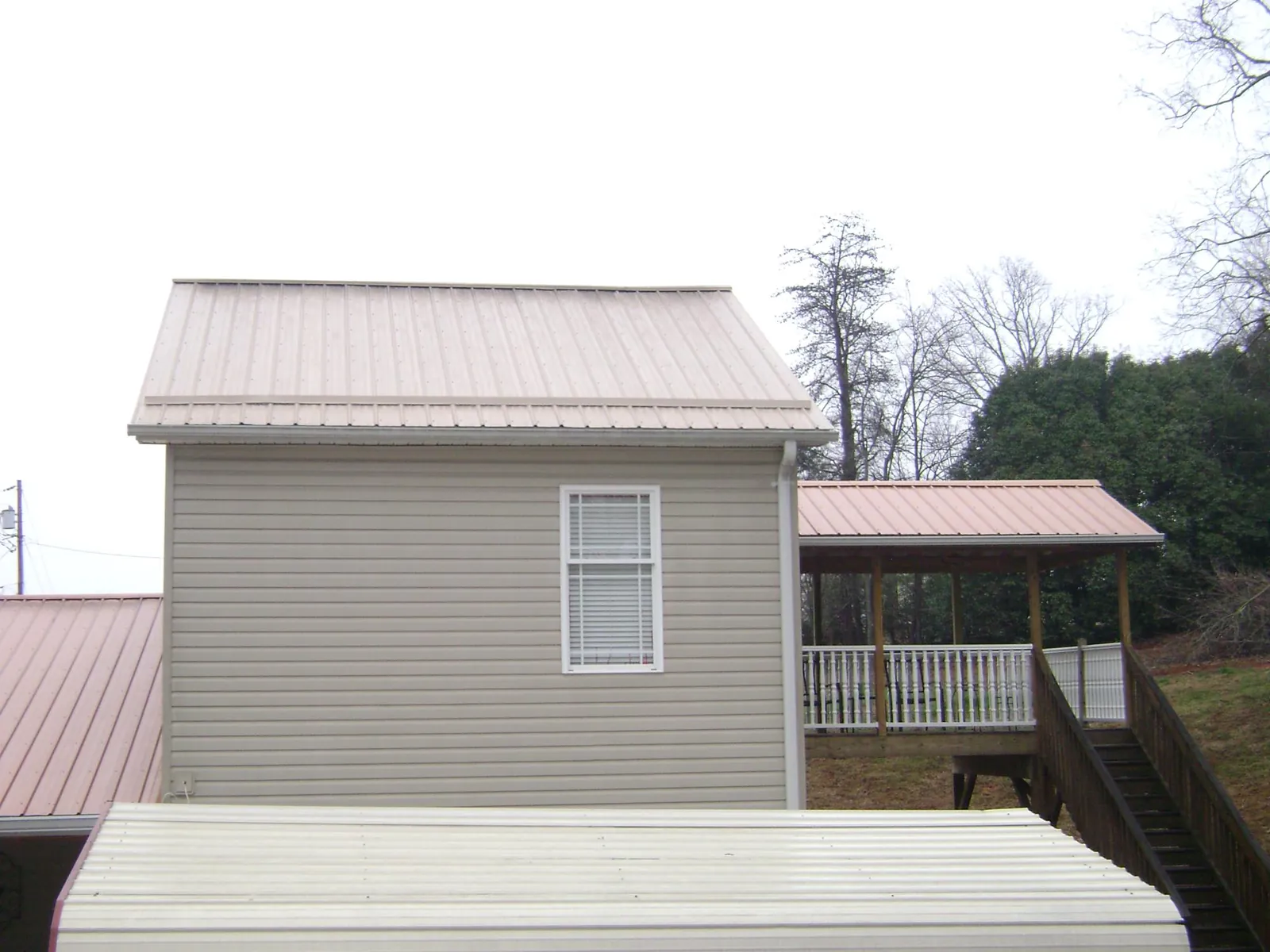 Tan metal roofs on a two story addition and attached porch, from a Roof Replacement job in Lodi