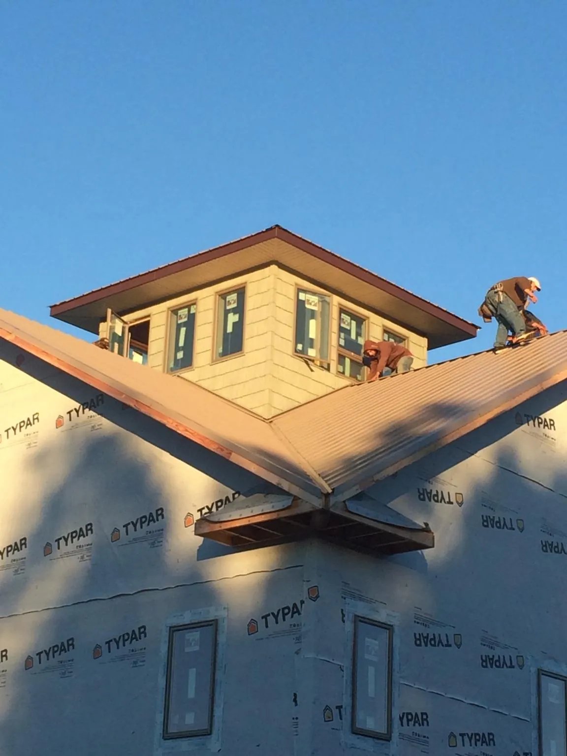 Roofers working around a rooftop cupola on a new metal roof at sunset — Roof Waterproofing in Lodi by Roofing Brothers